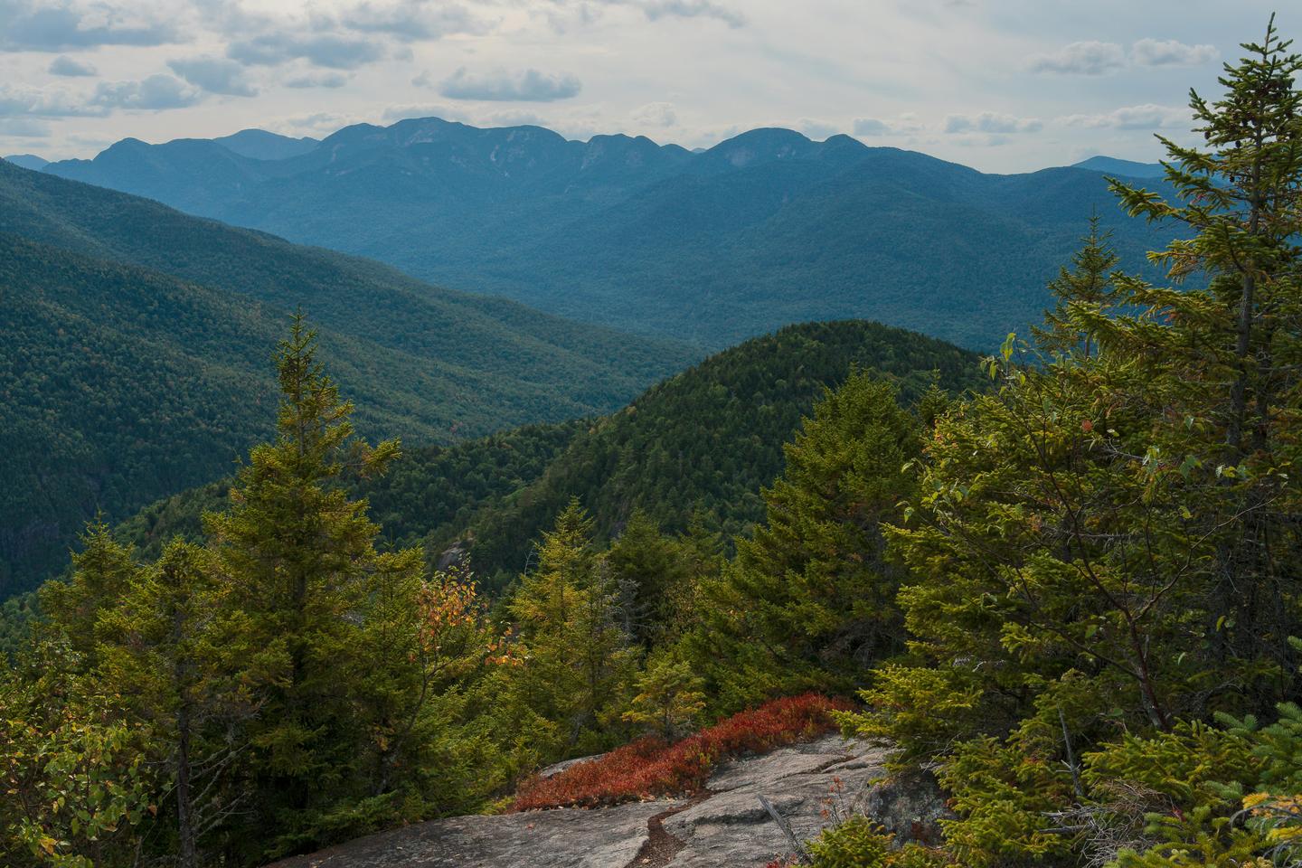 Scenic view of Adirondack Mountains with lush greenery, water, and mountain peaks in upstate New York