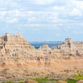 Formations rocheuses stratifiées et buttes dramatiques au parc national Badlands sous le vaste ciel du Dakota du Sud