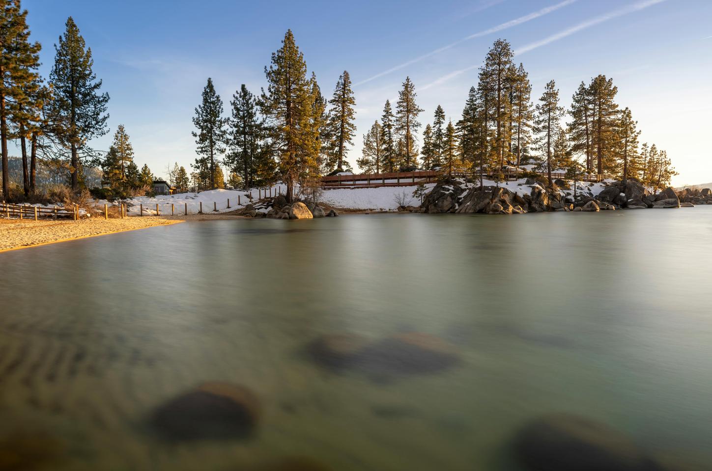 Crystal clear Lake Tahoe surrounded by snow-capped mountains and pristine forest