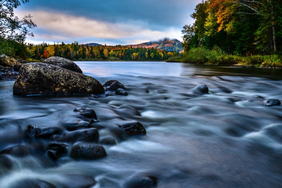 Scenic autumn river in Mont-Tremblant National Park surrounded by vibrant fall foliage in the Laurentians