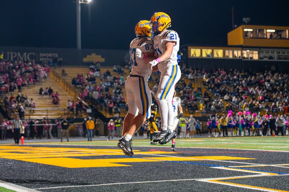 Football fans celebrating during an exciting night game at a packed stadium with vibrant energy and team pride