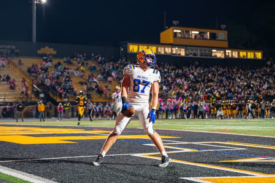Excited football player celebrating a touchdown during a thrilling night game in a packed stadium