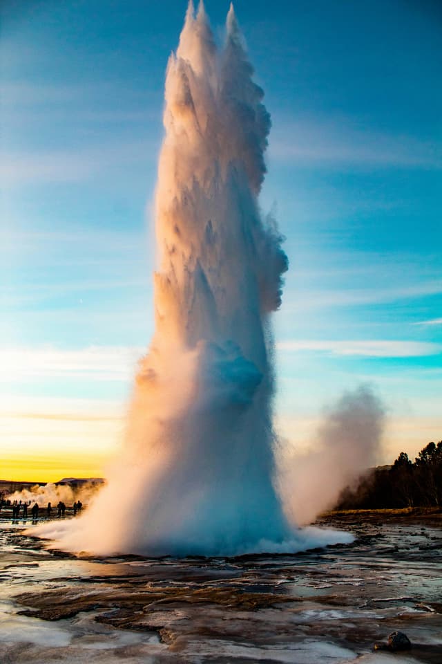 A powerful geyser eruption during sunset at Yellowstone National Park, showcasing nature's intensity
