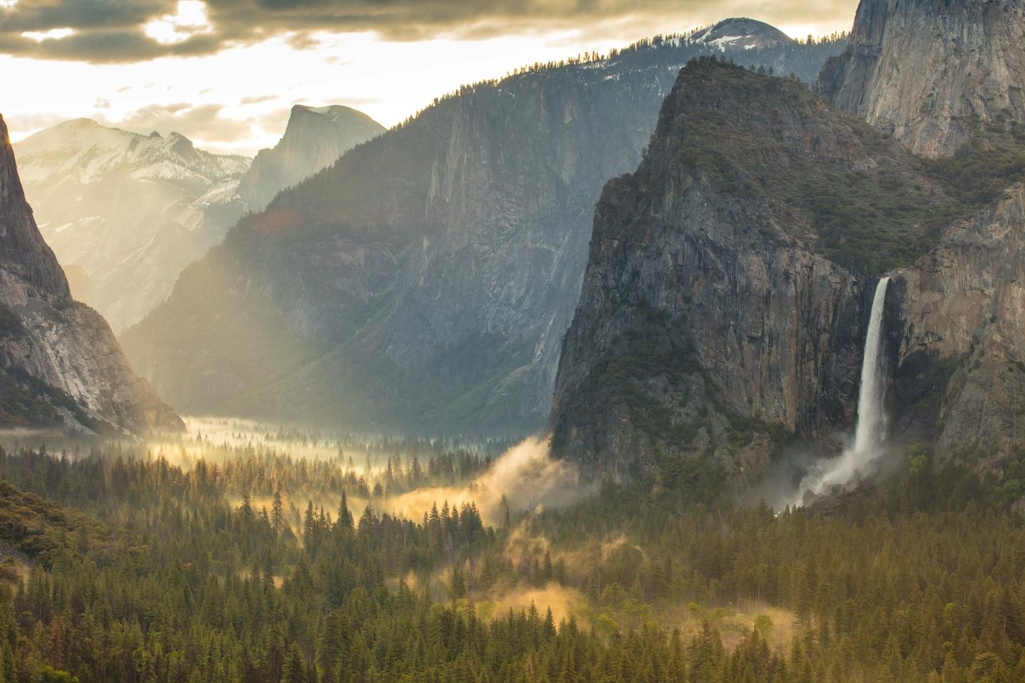 Breathtaking view of Yosemite Valley with a majestic waterfall cascading down the cliffs at sunset
